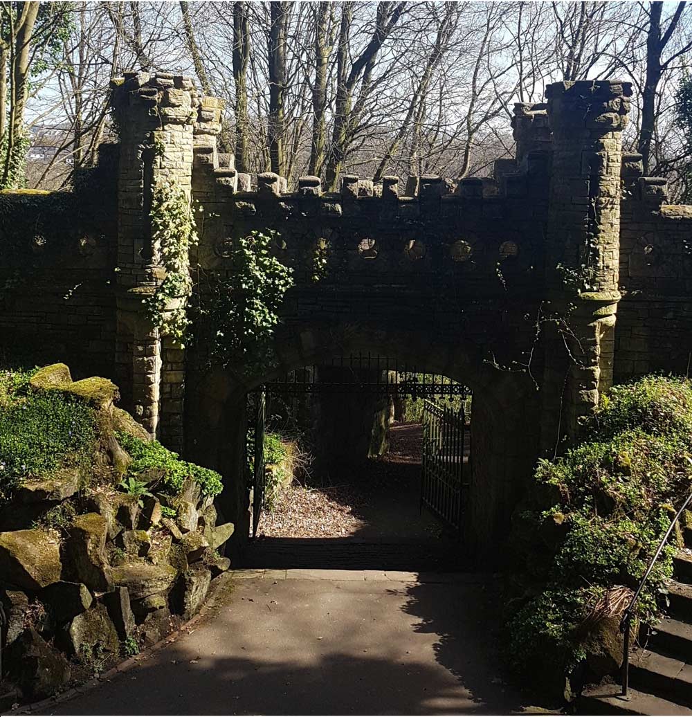 A photograph of a castle wall with a gate and path passing through it.